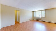 Located at 251 Yosemite Cir N in Golden Valley, MN, this one-bedroom, one-bathroom unit offers a well-organized, single-level layout designed for practical everyday living. The open living room serves as the heart of the space, featuring warm hardwood-style flooring, neutral wall tones, and large windows dressed with vertical blinds that allow abundant natural light to fill the room. A wall-unit air conditioner and baseboard heating ensure year-round comfort. A pendant chandelier adds a subtle decorative touch near the dining area. The galley-style kitchen is efficiently designed with rich wood cabinetry, granite-look countertops, a double stainless steel sink, and stainless steel appliances including a refrigerator and electric range. The hallway connects the main living areas to the private bedroom, which features plush carpeting, a built-in closet with shelving, and a large window that brings in natural light. Three closets throughout the unit provide generous storage. The bathroom is neatly appointed with mosaic tile flooring, white square tile wainscoting, a dark vanity with an integrated sink, and a full soaking tub. The overall aesthetic is clean, bright, and functional, making this a practical home in a convenient Minnesota location.