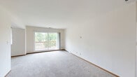 This well-designed single-floor residence in Waukesha, WI offers a practical and comfortable layout across a generously sized floor plan. The open-concept living and dining area is bright and inviting, finished with plush carpeting and anchored by a ceiling fan overhead. A large sliding glass door floods the space with natural light and provides direct access to a private balcony with outdoor views of mature trees, making it a standout feature of the living area.

The kitchen flows seamlessly from the living space via a curved breakfast bar peninsula, offering efficient galley-style functionality. Warm wood cabinetry lines the walls from floor to ceiling, complemented by light countertops, a stainless steel sink, and a full suite of black appliances including a refrigerator, electric range, and over-the-range microwave. Light wood-style flooring completes the kitchen's clean, practical aesthetic.

The bedroom is carpeted and neutral in tone, providing a quiet retreat. The residence includes two full bathrooms: one features a standalone shower stall with a sliding glass enclosure and tile flooring with a wood-tone vanity, while the second includes a full soaking tub with a shower combination. Both bathrooms are finished with light countertops and clean, functional fixtures throughout.