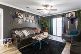 Located at 4900 E University Blvd in Odessa, Texas, this single-story residence offers a thoughtfully arranged layout with distinct living areas, a functional kitchen, multiple bedrooms, and two full bathrooms. The living room makes a bold impression with deep charcoal walls adorned with an eclectic gallery wall, dark leather sofas, a cowhide-print bench with turquoise legs, and rich wood-look flooring. A ceiling fan with integrated lighting anchors the space, while sliding glass doors invite natural light and provide outdoor access. The kitchen is outfitted with dark espresso cabinetry, marble-look countertops, a classic white subway tile backsplash, and black appliances, all illuminated by recessed lighting. A second living area or flex room features carpeted flooring, a ceiling fan, and a large window, currently used as a music room. The carpeted bedrooms include sliding door access to outdoor areas and ceiling fans, offering comfortable and versatile spaces. Both bathrooms are finished with wood-look flooring, dark vanity cabinetry, marble-look countertops, and tub-shower combinations with clean white tile surrounds. Throughout the home, a consistent mix of dark and neutral tones creates a cohesive, personality-filled atmosphere.