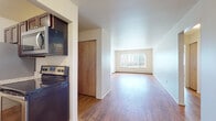 Located at 206 E Malcolm X St in Lansing, Michigan, this single-floor unit offers a functional and comfortable layout designed for everyday living. Warm hardwood-style flooring runs throughout the main living areas, lending a cohesive and inviting feel to the space.

The living area is generously proportioned, bathed in natural light from a large picture window that frames views of the surrounding cityscape. A wall-mounted air conditioning unit and baseboard heating ensure year-round comfort. The open layout connects seamlessly to the kitchen and adjoining spaces.

The kitchen is efficiently designed, featuring rich dark cabinetry, light granite-style countertops, a stainless steel sink, and a full suite of stainless steel appliances — including a refrigerator, electric range, and over-the-range microwave. A closet near the kitchen provides additional storage.

The bedroom is a quiet, well-lit room with a large window fitted with vertical blinds, a closet, and baseboard heating. The bathroom is clean and straightforward, with a full tub and shower combination, a curved shower rod, a toilet, and a vanity with dark cabinetry — all finished with tile flooring and a small window for natural ventilation.

Overall, this unit offers a clean, practical, and comfortable living environment in the heart of Lansing.