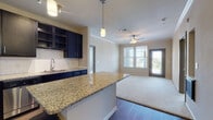 This single-floor residence is thoughtfully designed with a cohesive blend of modern finishes and functional layout. The kitchen serves as a central highlight, showcasing dark navy cabinetry with open shelving accents, granite countertops, a subway tile backsplash, and a full suite of stainless steel appliances including a refrigerator, range, microwave, and dishwasher. A kitchen island provides additional prep and seating space, while pendant lighting adds a refined touch. The kitchen flows seamlessly into the living area, which features wood-style flooring, a ceiling fan, and access to a private balcony that offers views of the surrounding landscape.

The bedrooms are carpeted and generously sized, each fitted with ceiling fans and large windows that bring in abundant natural light and outdoor views. The primary bedroom includes direct access to a private bathroom and a dedicated walk-in closet. The bathrooms are finished with granite-topped dark vanities, wood-style flooring, large-format white tile surrounds, and soaking tubs with shower combinations. A second full bathroom serves the additional bedroom. Throughout, the neutral color palette and consistent finishes create a cohesive and inviting atmosphere.