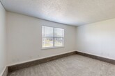 Located on East Gore Boulevard in Lawton, Oklahoma, this single-story, 2-bedroom, 2-bathroom home offers a practical and comfortable layout. The floor plan features a split-level design, with the bedrooms elevated slightly from the main living areas — a subtle architectural detail visible in the step transition between spaces. Both bedrooms are generously sized, with the primary bedroom offering notably spacious proportions. Soft, neutral carpet covers the bedroom floors, complemented by textured ceilings and white blinds on the windows that allow for natural light while maintaining privacy. The primary bedroom is outfitted with a ceiling fan and light fixture, adding both comfort and functionality. The second bedroom also features a large window with a window blind, keeping the room bright and airy. The bathrooms are finished with wood-toned cabinetry, light countertops, and hard surface wood-look flooring, while one bathroom includes a full tub and shower combination. A dedicated closet provides additional storage. The hallway connecting the rooms features hard surface flooring, smooth transitions between areas, and recessed lighting. Overall, the home presents a clean, neutral palette throughout, making it a versatile and move-in ready space.