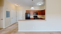 Located at 830 Holt Rd in Webster, NY, this single-floor residence offers a well-organized layout with a seamless flow between living, dining, and kitchen areas. The kitchen is a functional highlight, outfitted with rich cherry wood cabinetry, a full suite of black appliances including a refrigerator, gas range, microwave, and dishwasher, as well as a peninsula breakfast bar with a pendant light overhead — ideal for casual dining or additional prep space. Stone-look tile flooring runs throughout the kitchen and connects to the adjacent areas with ease.

The bedroom is comfortably carpeted and features a ceiling fan with light fixture, a window with blinds allowing natural light to fill the room, and a clean, neutral color palette throughout. The full bathroom includes a tub/shower combination with a curved curtain rod, a cherry wood vanity with storage, a framed mirror with overhead lighting, and matching tile flooring.

A dedicated laundry area houses a stacked washer and dryer unit, adding everyday convenience directly within the residence. The overall design is practical and cohesive, with warm neutral tones, consistent cabinetry finishes, and durable flooring choices that unify the space. This unit offers a comfortable and functional living environment in a residential community setting.