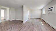 Located at 464 Spencerport Rd in Rochester, NY, this 2-bedroom, 1-bathroom unit offers a clean, move-in-ready layout across a single floor. The living area is spacious and bright, featuring durable wood-style vinyl plank flooring, neutral gray walls, textured ceilings, and multiple windows that allow natural light to fill the room. A wall-mounted AC unit and baseboard heating are present throughout. The kitchen is efficiently designed with white cabinetry, a stainless steel refrigerator, dishwasher, and range, complemented by light wood-style flooring that ties the space together. A hallway connects the main living areas to the bedrooms and bathroom, providing a logical flow throughout the unit. The primary bedroom is a well-proportioned room offering plush carpeting, a window with natural light, and baseboard heating. The second bedroom also features carpet flooring and a window. The bathroom includes a white vanity with an integrated sink, brushed nickel hardware, and wood-style flooring that mirrors the rest of the unit. Clean white trim and panel doors are consistent throughout, contributing to a cohesive and tidy aesthetic.