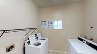 This laundry facility in Lewisville offers a clean and functional space designed to meet everyday laundering needs. The room is finished with neutral, warm-toned walls and light tile flooring, creating a bright and welcoming environment. Commercial-grade top-load washing machines and dryers are neatly arranged and readily accessible, providing reliable performance for users. A small window allows natural light to filter into the space, enhancing the overall brightness of the room. Instructional guides for washing and drying are posted on the wall, ensuring ease of use for all visitors. A wall-mounted rack provides additional utility, offering a convenient space for hanging or organizing items. The room maintains a tidy, well-kept appearance with ample space to move comfortably. The single-floor layout ensures straightforward accessibility, making this facility a convenient and efficient stop for laundry needs.