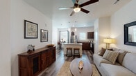 This single-story residence on Evergreen Street in Gardner, Kansas, presents a well-designed open-concept layout that seamlessly connects the living, dining, and kitchen areas. The living room features wood-look plank flooring, a ceiling fan, and generous wall space, creating a comfortable and airy atmosphere. A large framed mirror above the sofa enhances the sense of space, while multiple doors offer convenient access to adjoining rooms.

The kitchen is a standout feature, equipped with rich dark-walnut cabinetry, granite countertops, and a full suite of stainless steel appliances, including a refrigerator, range, and microwave. A central island with bar seating adds both functionality and style. Pendant lighting and recessed fixtures illuminate the space effectively. Adjacent to the kitchen, a dedicated dining nook benefits from abundant natural light through large windows with blinds and a glass door.

The bedrooms offer a calm retreat, each with plush carpeting, ceiling fans, and natural light. The primary bedroom includes direct access to a private bath. A secondary bathroom features wood-look flooring, a vanity, and clean white walls. Throughout the home, neutral tones and warm wood accents create a cohesive, modern aesthetic.