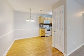 Located at 405 Guilford College Rd in Greensboro, NC, this single-floor, 2-bedroom, 2-bathroom home offers a well-designed layout across a comfortable footprint. The open living and dining area is bright and welcoming, with large windows allowing abundant natural light and views of surrounding greenery. The dining space is accented by an elegant chandelier and classic chair-rail molding, adding a refined touch to the neutral, light-toned walls. Smooth hardwood-style flooring flows through the living, dining, and kitchen areas, creating a cohesive aesthetic throughout the main spaces. The kitchen is efficiently designed, featuring light wood cabinetry, a mosaic tile backsplash, grey countertops, and white appliances including a range, built-in microwave, dishwasher, and refrigerator. Both bedrooms are carpeted for comfort and include windows with garden views; the primary bedroom also features a ceiling fan. Each bedroom is supported by a dedicated closet, and the two bathrooms include tub/shower combinations with tile flooring. The textured ceilings throughout add dimension, while the neutral color palette keeps the space feeling clean and move-in ready.