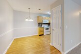 Located at 405 Guilford College Rd in Greensboro, NC, this single-floor, 2-bedroom, 2-bathroom home offers a well-designed layout across a comfortable footprint. The open living and dining area is bright and welcoming, with large windows allowing abundant natural light and views of surrounding greenery. The dining space is accented by an elegant chandelier and classic chair-rail molding, adding a refined touch to the neutral, light-toned walls. Smooth hardwood-style flooring flows through the living, dining, and kitchen areas, creating a cohesive aesthetic throughout the main spaces. The kitchen is efficiently designed, featuring light wood cabinetry, a mosaic tile backsplash, grey countertops, and white appliances including a range, built-in microwave, dishwasher, and refrigerator. Both bedrooms are carpeted for comfort and include windows with garden views; the primary bedroom also features a ceiling fan. Each bedroom is supported by a dedicated closet, and the two bathrooms include tub/shower combinations with tile flooring. The textured ceilings throughout add dimension, while the neutral color palette keeps the space feeling clean and move-in ready.