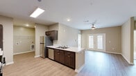 Located in Greenville, SC, this single-floor, three-bedroom, two-bathroom home offers a well-designed layout with a blend of comfort and functionality. The open-concept living and kitchen area serves as the heart of the home, featuring light wood-style flooring, recessed lighting, and a ceiling fan. The kitchen is outfitted with rich dark-wood cabinetry, light stone countertops, stainless steel appliances including a refrigerator, dishwasher, and range, and a peninsula with a sink that overlooks the living area. French doors in the living room fill the space with natural light. The galley-style kitchen provides ample cabinetry and counter space, with a dedicated laundry area accessible from the kitchen. The three bedrooms are carpeted and each includes a ceiling fan. The primary bedroom is generously sized and features natural light from dual windows, a walk-in closet with wire shelving, and direct access to a bathroom. The two full bathrooms are finished with dark-wood vanities, light countertops, light wood-style flooring, and tub-shower combinations. A dedicated closet provides additional storage. Neutral warm-toned walls throughout create a cohesive and inviting ambiance.