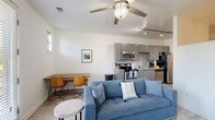 Located at 1016 18th Ave S in Nashville, TN, this single-floor unit offers a well-organized layout that efficiently combines everyday living spaces. Light wood-style flooring runs throughout, creating a cohesive and clean aesthetic from room to room.

The kitchen is a functional highlight, outfitted with gray shaker-style cabinetry, granite countertops, a subway tile backsplash, and a full suite of stainless steel appliances including a refrigerator, electric range, microwave, and dishwasher. Track lighting overhead and a window allow natural light to fill the space. The kitchen flows directly into a combined dining and living area, where a ceiling fan, multiple windows, and a glass door leading to a private balcony bring in ample natural light and views of the surrounding greenery.

The living area provides a comfortable, open setting with enough room for a sofa, accent chair, coffee table, and entertainment unit. The private balcony access adds an outdoor dimension to the living space.

The bathroom features a clean, minimalist design with wood-plank-style tile flooring, a modern vanity with under-cabinet storage, a wall-mounted mirror, and a shower-tub combination. White walls and well-placed lighting contribute to a bright, tidy feel. The unit also includes a dedicated sleeping area visible in the floorplan, completing a practical and thoughtfully designed layout.