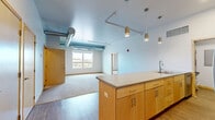 Located at 101 Virginia St, Unit 414, in Sioux City, Iowa, this 2-bedroom, 2-bathroom residence offers a thoughtfully designed single-floor layout. The open-concept living area seamlessly integrates the kitchen, dining, and living spaces into one generous, light-filled room. The kitchen is equipped with stainless steel appliances, light maple cabinetry, a tile backsplash, and a large island with a stone-look countertop and pendant lighting above — an ideal setup for both cooking and entertaining. Wood-style plank flooring anchors the main living area, while plush carpet provides comfort in the bedrooms and living space.

The primary bedroom offers a comfortable footprint with exposed industrial-style ductwork adding architectural character, along with a dedicated walk-in closet featuring wire shelving. A second bedroom of similar style provides flexibility for guests or a home office. Both bathrooms are finished with light maple vanities and gray countertops; one includes a walk-in shower, while the other features a full soaking tub. An in-unit laundry area adds everyday convenience. With four closets total throughout the unit, storage is plentiful. The space combines modern finishes with an industrial aesthetic for a distinctive urban living experience.