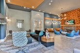 Located at 811 Park St SW in Atlanta, Georgia, this single-floor amenity space delivers a polished, contemporary environment with thoughtfully curated design elements throughout. The open floor plan flows seamlessly from zone to zone, creating a sense of generous, connected space.

The central lounge area serves as a striking focal point, anchored by a linear fireplace set into a dramatic textured wood accent wall. Teal upholstered lounge chairs surround a sculptural coffee table beneath a sputnik-style chandelier, evoking a warm yet modern atmosphere. Soaring ceilings with warm wood paneling and large floor-to-ceiling windows flood the space with natural light and offer views of the surrounding streetscape.

The fully equipped kitchen features deep navy cabinetry, a large granite-topped island, double stainless steel wall ovens, and open floating shelves with warm wood accents. Deep teal tile backsplash adds a refined, cohesive touch. A bar-height counter with sleek black seating transitions the kitchen toward the main entry, where additional lounge and café-style seating areas provide flexible gathering options. Throughout, large-format stone tile flooring, curated artwork, and layered lighting reinforce a cohesive, upscale aesthetic.