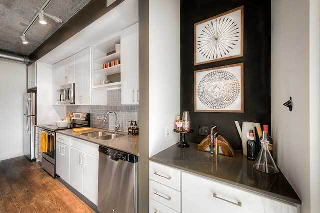 Kitchen with white cabinetry, quartz countertops, stainless steel appliances, tile backsplash and hard surface flooring - AVA NoMa