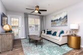 Located at 540 S Carroll Rd in Villa Rica, Georgia, this single-floor residence offers a thoughtfully designed layout that balances comfort and functionality throughout. The kitchen is a standout feature, showcasing crisp white cabinetry, granite-style countertops, a decorative mosaic tile backsplash, and black appliances including a range, microwave, and dishwasher, all set atop warm wood-look flooring. Adjacent to the kitchen, the dining area provides an intimate setting with wood flooring and a modern overhead light fixture. The living room is a welcoming retreat, featuring wood-look flooring, neutral-toned walls, a ceiling fan, and generous natural light streaming through large windows dressed with blinds and floor-length drape panels. The bedrooms are carpeted for comfort, each benefiting from natural light through well-sized windows. The primary bedroom connects to a private bathroom, while additional bedrooms share a well-maintained full bathroom featuring wood-look flooring, a vanity with a granite-style countertop, a large mirror, and a shower-tub combination. Throughout the home, neutral gray walls, clean trim work, and consistent flooring choices create a cohesive and move-in-ready aesthetic.