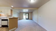 Located at 2600 W Lakewood Ln in Oak Creek, Wisconsin, this single-floor unit offers a straightforward, functional layout designed for comfortable everyday living. The open-concept living area is carpeted and features a textured ceiling, neutral walls, and a sliding glass door that fills the space with natural light while providing direct access to an outdoor green area. A low breakfast bar separates the living space from the kitchen, offering a natural transition between the two areas.

The kitchen is equipped with white cabinetry, light countertops, a coil-burner electric range with an overhead ventilation hood, and a dishwasher. Ample cabinet storage lines the walls, keeping the workspace organized and practical. The layout is efficient, making good use of the available space.

The bathroom features stone-look tile flooring in warm earth tones, a full-sized bathtub with a tub surround, and standard fixtures. The space is clean and functional. Additional features throughout the unit include louvered closet doors providing generous storage, and the overall floor plan, visible in the 3D overview, shows a well-organized single-level arrangement with private spaces clearly defined toward the rear of the unit.