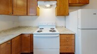 Located at 149 Portland Ave in Dover, NH, this single-floor unit offers a practical and comfortable layout with consistent design details throughout. Rich, dark hardwood-style flooring runs through the main living areas and bedrooms, providing a warm and cohesive aesthetic. The spacious living room features a textured ceiling, a wall-mounted air conditioning unit, baseboard heating, and access to an outdoor balcony, allowing for natural light to fill the space. The kitchen is well-appointed with warm-toned wood cabinetry, light stone-effect countertops, a white electric range with overhead ventilation, and a refrigerator, offering ample storage and prep space. The bedrooms are bright and generously sized, each featuring large windows that frame views of surrounding trees and wooded scenery, along with baseboard heating for year-round comfort. The bathroom is clean and functional, featuring a full tub and shower combination with built-in shelving, a toilet, and a wood-finish vanity with a white countertop, complemented by tile flooring. Crisp white walls and white trim throughout the unit create a clean, neutral backdrop. The overall ambiance is practical and inviting, with natural surroundings visible from multiple rooms enhancing the sense of tranquility.