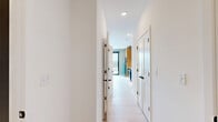 Located at 1923 Broadway Blvd in Kansas City, MO, this thoughtfully designed one-bedroom, one-bathroom unit offers a compact yet efficient layout on a single floor. The open-concept kitchen is the centerpiece of the space, showcasing striking two-tone cabinetry that pairs warm wood uppers with bold blue lower cabinets, illuminated by under-cabinet lighting. A large white quartz island provides ample prep and dining space, while the stainless steel apron-front farmhouse sink and marble-look backsplash add refined detail. Stainless steel appliances, including a distinctive teal refrigerator, complete the modern aesthetic. Light hardwood flooring flows throughout the main living area, enhancing the bright, airy atmosphere. A floor-to-ceiling sliding glass door opens to a balcony with sweeping views of the Kansas City skyline, flooding the space with natural light. The bedroom features soft neutral carpeting and clean white walls, offering a calm retreat. The bathroom is finished with large-format marble-look tile flooring, a dark wood vanity with gold hardware accents, and a sleek, frameless glass shower with deep navy tile — a standout design element that adds sophistication to the overall space.