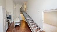 Located on Sunrise Valley Drive in Reston, Virginia, this two-story, two-bedroom, two-bathroom home offers a well-designed layout spread across two thoughtfully proportioned floors. The lower level features rich hardwood flooring, a modern kitchen equipped with stainless steel appliances and light cabinetry, and a striking open staircase with a metal railing that rises dramatically to the upper floor. The soaring double-height ceiling and large windows flood the main living area with abundant natural light and provide pleasant views of the surrounding tree-lined streetscape. A clean, modern half-bath on this level features a white quartz vanity, under-mount sink, and sleek fixtures. Upstairs, both bedrooms are carpeted and finished with neutral tones. The primary bedroom includes a sliding barn door—a stylish architectural detail—and opens to a private balcony overlooking the greenery outside. The second bedroom features a built-in closet and direct access to the full bathroom, which is outfitted with subway tile, a soaking tub, a white quartz vanity with gray cabinetry, and large-format tile flooring. A dedicated closet adds practical storage. The home's clean, contemporary aesthetic is carried throughout with consistent neutral finishes, modern lighting, and an efficient two-floor plan.