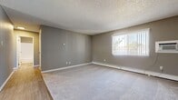 This well-appointed 3-bedroom, 1-bathroom home offers a practical and comfortable single-floor layout. The living room is a welcoming space featuring neutral gray walls, plush carpeting, a textured ceiling, and a large window that fills the room with natural light while offering outdoor views. Baseboard heating runs throughout the home, ensuring warmth and comfort year-round.

The kitchen stands out with crisp white shaker-style cabinetry, light stone countertops, wood-look vinyl plank flooring, and a full suite of stainless steel appliances including an electric range, over-the-range microwave, and dishwasher. A window above the sink adds natural light to this functional cooking space.

All three bedrooms continue the home's consistent aesthetic of gray walls, soft carpet, and baseboard heating. Each room receives natural light through windows dressed with vertical blinds. The spacious primary bedroom offers generous room for furnishings. The two additional bedrooms are well-proportioned and versatile.

The bathroom is clean and functional, featuring wood-look vinyl flooring, a tub-shower combination, a single vanity with sink, and baseboard heating. The cohesive neutral palette and practical finishes throughout make this home a comfortable and move-in ready space.