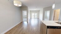 Located at 5477 200 St in Langley, BC, this well-appointed 2-bedroom, 2-bathroom unit offers a thoughtfully designed open-concept layout that maximizes its comfortable footprint. The kitchen is a standout feature, showcasing a large island with a white quartz countertop and double undermount sink, wood-toned cabinetry, a subway tile backsplash, and a full suite of stainless steel appliances including a refrigerator, electric range, and built-in microwave. Track lighting and pendant lights illuminate both the kitchen and the adjacent living area, which is finished with warm laminate hardwood flooring and neutral-toned walls that create a bright, welcoming ambiance. The primary bedroom is generously sized, featuring soft carpeting, a large window with outdoor views, and access to a well-appointed ensuite bathroom complete with a sliding glass walk-in shower, tile flooring, and a vanity with a taupe countertop. The second bedroom also features plush carpeting, a window overlooking the surrounding neighborhood, and a baseboard heater. A second full bathroom with a matching vanity and tile flooring serves this bedroom. The unit's clean, modern aesthetic is consistent throughout, making it a functional and attractive residence in the heart of Langley.