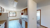 Located at 2835 Hawken St in Bismarck, North Dakota, this 2-bedroom, 1-bathroom unit offers a practical and comfortable single-floor layout. The kitchen and dining area flow together seamlessly, featuring warm wood-toned cabinetry with ample upper and lower storage, a double-basin sink, laminate countertops, and a full suite of appliances including a refrigerator, electric range, microwave, and dishwasher. Light wood-look flooring runs throughout the kitchen and dining space, while a window invites natural light into the area. The living room is generously proportioned, finished with plush carpet and a baseboard heating system. Both bedrooms are carpeted and bright, each benefiting from natural light through sliding windows that frame outdoor tree and landscape views. The primary bedroom includes dedicated closet space, and the unit overall features four closets for excellent storage. The full bathroom is clean and functional, equipped with a tub/shower combination, vanity, and wood-look flooring. A dedicated laundry room and a connecting hallway complete the unit's well-organized floor plan. Textured ceilings are consistent throughout, adding a classic finish to the space.