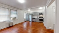 Located on Spruce Street in the heart of West Philadelphia's vibrant University City neighborhood, this single-floor unit offers a well-designed layout that blends classic architectural charm with modern updates. Rich, warm-toned hardwood floors run throughout the main living areas, creating a cohesive and inviting ambiance.

The open living and kitchen area forms the centerpiece of the space. The kitchen is outfitted with grey shaker-style cabinetry extending to the ceiling for generous storage, a full suite of stainless steel appliances including a gas range, microwave, dishwasher, and refrigerator, and a clean white tile backsplash. Multiple windows along the living area wall allow natural light to fill the room, complemented by cast-iron radiators that speak to the building's classic construction.

Crown molding and a defined archway between the living and bedroom areas add refined architectural detail. The bedroom is a spacious, quiet retreat with a closet and an arched nook, continuing the warm hardwood flooring. The bathroom features dark tile flooring, a white vanity, and a tiled shower-tub combination, maintaining a clean and functional aesthetic throughout. The overall design balances period character with contemporary convenience.