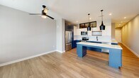 Located at 1711 Commonwealth Ave in Charlotte's vibrant 28205 corridor, this well-appointed one-bedroom, one-bathroom unit offers a thoughtfully designed open-concept floor plan. The combined living, dining, and kitchen area serves as the heart of the home, anchored by a striking kitchen featuring bold navy-blue cabinetry, crisp white upper cabinets, a classic subway tile backsplash, stainless steel appliances, and a large waterfall-edge quartz island illuminated by sleek matte black pendant lights. Wood-look flooring flows seamlessly throughout, complementing the neutral gray walls and clean white trim. The living area benefits from natural light through large windows and a glass-panel entry door that brightens the space. The bedroom is a comfortable, well-proportioned retreat with a ceiling fan, high transom windows that allow in additional light, and access to multiple closets for generous storage. The full bathroom is finished with white tile surrounds, a soaking tub, matte black fixtures, and a clean white vanity. The overall design palette is modern and cohesive, balancing contemporary finishes with a welcoming, functional layout ideal for everyday living.