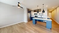 Located at 1711 Commonwealth Ave in Charlotte's vibrant 28205 corridor, this well-appointed one-bedroom, one-bathroom unit offers a thoughtfully designed open-concept floor plan. The combined living, dining, and kitchen area serves as the heart of the home, anchored by a striking kitchen featuring bold navy-blue cabinetry, crisp white upper cabinets, a classic subway tile backsplash, stainless steel appliances, and a large waterfall-edge quartz island illuminated by sleek matte black pendant lights. Wood-look flooring flows seamlessly throughout, complementing the neutral gray walls and clean white trim. The living area benefits from natural light through large windows and a glass-panel entry door that brightens the space. The bedroom is a comfortable, well-proportioned retreat with a ceiling fan, high transom windows that allow in additional light, and access to multiple closets for generous storage. The full bathroom is finished with white tile surrounds, a soaking tub, matte black fixtures, and a clean white vanity. The overall design palette is modern and cohesive, balancing contemporary finishes with a welcoming, functional layout ideal for everyday living.