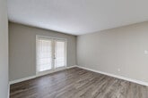 Located at 1606 Pinecroft Rd in Greensboro, North Carolina, this one-bedroom, one-bathroom unit offers a practical and well-organized single-floor layout. Throughout the space, warm-toned wood-look flooring provides a consistent and cohesive aesthetic, complemented by neutral gray walls and crisp white baseboards and trim.

The living room is a comfortable, open area highlighted by French doors that allow natural light to fill the room and provide a direct connection to the outdoors. Adjacent to the living space, a pass-through counter connects to the kitchen, which features light granite-style countertops and includes a refrigerator — ideal for an efficient, functional setup.

The bedroom is a well-proportioned private retreat with its own window fitted with blinds for light control and privacy. A textured ceiling adds subtle character throughout. The bedroom connects conveniently to a hallway leading to a dedicated closet for storage.

The bathroom is finished in a clean, all-white palette, featuring a tub-shower combination, a toilet, and overhead cabinetry that provides additional storage above the toilet. The space flows efficiently through a short hallway connecting all rooms. Overall, the unit presents a tidy, move-in-ready interior with a straightforward and functional design.