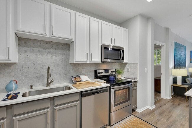 Modern kitchen with sleek appliances, elegant cabinetry, and stylish hexagonal backsplash, showcasing open-concept design. - Avia Lowry