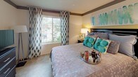 Located at 1403 Kirts Blvd in Troy, Michigan, this single-floor residence offers a cohesive and thoughtfully designed interior highlighted by a consistent teal, yellow, and neutral color palette throughout. Light wood-style flooring runs through the main living areas, contributing to a bright and cohesive aesthetic.

The living room is a comfortable, open space featuring large sliding glass doors that invite natural light and provide direct outdoor access and exterior views. An in-unit stacked washer and dryer is conveniently housed within a dedicated closet in this area. The kitchen is well-equipped with rich dark cabinetry, granite-style countertops, stainless steel appliances including a refrigerator, range, and microwave, and a peninsula that opens toward the living space.

The dining area is distinguished by a bold teal accent wall adorned with decorative stenciling, complemented by a dark dining table and patterned drapery along the adjacent window.

The bedroom offers carpeted flooring, a large window with outdoor views, and a closet with panel doors, providing a quiet and functional retreat. A secondary space serves well as a home office or guest room, also with carpeted floors and striped accent walls.

The bathroom features a tub and shower combination with sliding glass doors, wood-toned vanity cabinetry, and a tiled surround, finished with teal accent walls that tie into the overall design theme.