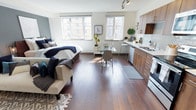 This well-appointed studio unit on the fourth floor of 1800 S Jackson St offers a thoughtfully designed open-plan layout that maximizes every square foot. Rich, dark hardwood floors run throughout the space, lending warmth and a sense of continuity from the living area through to the kitchen.

Natural light pours in through two generously sized windows, brightening the interior and creating an airy, welcoming ambiance. The sleeping area is comfortably integrated into the main living space, while a dedicated dining nook with a glass-top table and bar seating provides a functional area for meals and work.

The kitchen is modern and efficient, featuring warm wood-toned cabinetry, white appliances, a subway tile backsplash, and a sleek countertop with ample prep space. A stainless steel sink sits beneath a window, adding to the brightness of the cooking area.

Track lighting on the ceiling supplements natural light and adds a contemporary touch to the overall design. White walls keep the space feeling open and clean, complementing the rich tones of the flooring and cabinetry. Located in Seattle's Jackson Place neighborhood, this studio combines urban convenience with a comfortable, cohesive interior aesthetic.