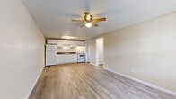 This efficient one-bedroom, one-bathroom unit is thoughtfully laid out across a single floor, making smart use of every square foot. Light wood-style luxury vinyl flooring runs throughout the entire space, creating a cohesive and easy-to-maintain aesthetic. The open-concept living area flows directly into the kitchen, maximizing the sense of space. A large front-facing window floods the living room with natural light, while a ceiling fan with integrated lighting provides comfort and ventilation. A wall-mounted PTAC unit offers dedicated climate control.

The kitchen is well-equipped, featuring white shaker-style cabinetry that extends to the ceiling for generous storage, dark countertops, a stainless sink, and white appliances including a refrigerator and electric range. An overhead skylight-style fixture provides additional task lighting.

The bedroom is a comfortable size, complete with its own ceiling fan, a large window that brings in natural light, and direct access to the hallway. The bathroom is cleanly finished with wood-look tile flooring, a single-sink vanity with white cabinetry, a toilet, and a full tub-shower combination. Neutral warm beige walls and white trim carry throughout the unit, contributing to a clean, move-in-ready presentation.
