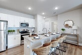 This single-story residence in Pensacola, Florida offers a thoughtfully designed open-concept layout finished with warm neutral tones and light wood-style flooring throughout. Recessed lighting illuminates each room, complemented by ceiling fans in both the living area and bedroom for year-round comfort.

The kitchen is a standout feature, showcasing crisp white shaker cabinetry, granite countertops, and a blue subway tile backsplash. Stainless steel appliances—including a refrigerator, range, and built-in microwave—provide a polished, functional workspace. A multi-seat island with granite counters serves as a natural gathering point, flowing seamlessly into the open living area.

The living room is generously proportioned, offering ample space for comfortable seating arrangements. Its open connection to the kitchen creates an inviting, social atmosphere ideal for everyday living and entertaining.

The bedroom is a calm retreat with soft, neutral walls, hardwood-style flooring, a ceiling fan, and direct access to a walk-in closet with built-in shelving. The bathroom features white cabinetry, granite countertops, and a shower-tub combination, maintaining the clean, cohesive aesthetic found throughout the home.
