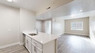 This single-floor, 2-bedroom, 2-bathroom residence offers a thoughtfully designed layout that maximizes functionality and comfort. The open-concept kitchen and living area serves as the heart of the home, featuring a large center island with a white quartz countertop and an undermount sink, white shaker-style cabinetry, and stainless steel appliances including a refrigerator, range, and microwave. Wood-look luxury vinyl flooring runs throughout the main living areas, lending a clean and cohesive aesthetic.

The living room receives natural light through a window with blinds, creating a bright and welcoming atmosphere. Both bedrooms are carpeted for added comfort, with the primary bedroom offering a generous footprint and the secondary bedroom featuring a windowed door that invites additional natural light. Each bedroom is finished in neutral tones, providing a calm and versatile backdrop.

The two bathrooms are identically appointed, each featuring a white vanity with quartz countertops, a tub-shower combination with a curved curtain rod, brushed nickel hardware, and wood-look flooring. The neutral color palette and modern fixtures carry consistently throughout the entire residence, resulting in a cohesive and move-in-ready living space.
