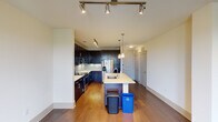 This modern single-floor residence in Grapevine, TX offers a thoughtfully designed open-concept layout with upscale finishes throughout. The kitchen is a standout feature, showcasing rich dark cabinetry, a light-colored quartz countertop with a spacious center island and undermount sink, stainless steel appliances including a French door refrigerator, gas range, and built-in microwave, as well as a sleek subway tile backsplash. Track and pendant lighting illuminate the space, creating a refined atmosphere that flows seamlessly into the living area. Warm hardwood flooring extends throughout the main living spaces, complemented by neutral-toned walls that enhance the bright, airy feel. The living area connects to a private balcony through glass-paneled French doors, allowing natural light to fill the room. The primary bedroom features the same hardwood flooring, a ceiling fan, and balcony access. The primary bath is generously appointed with a dual-sink vanity, dark cabinetry, a soaking tub, and a separate glass-enclosed shower with tile surround. Additional bedrooms are carpeted with ceiling fans and natural light. A spacious walk-in closet with built-in shelving and hanging rods provides ample storage.