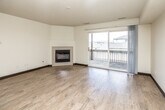 This single-floor residence offers a thoughtfully designed open layout that connects the main living areas with ease. The spacious living room is a standout feature, highlighted by light wood-style flooring, a textured ceiling, and a tiled corner fireplace that serves as a warm focal point. A large sliding glass door floods the space with natural light and opens directly onto a private balcony, offering views of the surrounding neighborhood rooftops.

The kitchen is efficiently arranged in an L-shaped configuration, outfitted with light oak cabinetry, ample counter space, a stainless steel double sink, and white appliances including a range and refrigerator. An over-the-range microwave adds everyday convenience. The adjacent entry area features durable wood-look flooring and a built-in shelving unit, providing practical storage from the moment you walk in.

The two bedrooms are carpeted for comfort and each features a generously sized closet with bi-fold doors and wire shelving systems. The full bathroom is clean and functional, with a single-sink vanity featuring oak cabinetry, a full-width mirror, and a tub-shower combination with a bright white surround. Light wood-style flooring in the bathroom ties cohesively into the rest of the space. Overall, the residence presents a practical and comfortable layout suited for everyday living.