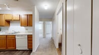 Located at 440 Meriden Rd in Waterbury, Connecticut, this single-floor residence offers a well-organized layout encompassing two bedrooms, one bathroom, and a connecting hallway. The home's interior is finished with neutral, warm-toned walls throughout, creating a bright and cohesive atmosphere.

Both bedrooms feature plush wall-to-wall carpeting and large windows fitted with blinds, allowing natural light to fill each room while offering outdoor views of the surrounding neighborhood. The primary bedroom includes a ceiling fan with a light fixture and a built-in closet with louvered bifold doors, providing ample storage. A textured ceiling is present throughout the living spaces.

The kitchen is outfitted with warm wood-toned cabinetry, a white appliance suite including a range and dishwasher, and a single-basin sink — offering a practical and functional cooking space.

The bathroom continues the warm wood cabinetry theme, featuring an extended vanity with a single sink, generous under-sink storage, and a large mirror. Wood-look flooring adds a clean, durable finish to the space.

The layout flows naturally from room to room via the hallway, making the overall floor plan efficient and easy to navigate. This residence provides a comfortable and functional living environment suitable for a variety of needs.