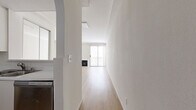 Located at 625 Hauser Blvd in the Mid-City neighborhood of Los Angeles, this single-floor 2-bedroom, 2-bathroom unit offers a clean, modern aesthetic throughout. Light wood flooring runs consistently across all rooms, lending warmth and visual continuity to the space.

The combined kitchen and living area forms the heart of the unit. The galley-style kitchen is efficiently laid out with white cabinetry, stainless steel appliances including a refrigerator and range, a dishwasher, and a single-basin sink — providing all essential amenities in a well-organized format. The adjacent living room is generous in scale, featuring neutral-toned walls, crown molding, and a built-in storage cabinet, creating a versatile and comfortable gathering space.

The primary bedroom offers a well-proportioned layout with a dedicated closet, while the second bedroom benefits from a large sliding window that frames views of surrounding greenery, filling the room with natural light. An additional bedroom features vertical blinds and ample sun exposure.

Both bathrooms are finished in crisp white with tub-shower combinations, vanity mirrors, and light wood flooring. A hallway connects the private areas of the unit with ease. An outdoor balcony provides a functional outdoor extension of the living space.