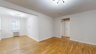 Located at 159 Grand Ave in Leonia, NJ, this single-floor unit offers a clean, modern aesthetic with thoughtful finishes throughout. Warm hardwood flooring flows seamlessly across the main living areas, lending a sense of continuity and comfort to the space.

The open living area is bright and airy, featuring crisp white walls, clean baseboards, and a contemporary multi-head ceiling light fixture. The layout provides generous room for furnishing and allows for flexible use of space.

The kitchen has been updated with dark shaker-style cabinetry, white countertops, a stainless steel sink, and a full suite of stainless steel appliances including a gas range, microwave, dishwasher, and refrigerator. A window allows natural light to fill the space.

The bedroom is a well-proportioned room with hardwood flooring, a window overlooking the neighborhood, and a classic cast-iron radiator that adds character while providing efficient heating. The entryway area also features a radiator, a front door with a transom window, and a conveniently tucked-in stacked washer and dryer unit.

The bathroom is elegantly finished with large-format marble-look wall tiles surrounding a soaking tub, brushed gold fixtures, a white vanity with under-cabinet storage, and a mirrored medicine cabinet — combining style with functionality.