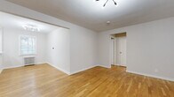 Located at 159 Grand Ave in Leonia, NJ, this single-floor unit offers a clean, modern aesthetic with thoughtful finishes throughout. Warm hardwood flooring flows seamlessly across the main living areas, lending a sense of continuity and comfort to the space.

The open living area is bright and airy, featuring crisp white walls, clean baseboards, and a contemporary multi-head ceiling light fixture. The layout provides generous room for furnishing and allows for flexible use of space.

The kitchen has been updated with dark shaker-style cabinetry, white countertops, a stainless steel sink, and a full suite of stainless steel appliances including a gas range, microwave, dishwasher, and refrigerator. A window allows natural light to fill the space.

The bedroom is a well-proportioned room with hardwood flooring, a window overlooking the neighborhood, and a classic cast-iron radiator that adds character while providing efficient heating. The entryway area also features a radiator, a front door with a transom window, and a conveniently tucked-in stacked washer and dryer unit.

The bathroom is elegantly finished with large-format marble-look wall tiles surrounding a soaking tub, brushed gold fixtures, a white vanity with under-cabinet storage, and a mirrored medicine cabinet — combining style with functionality.