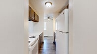 Located at 1205 S Chelton Rd in Colorado Springs, CO, this well-appointed one-bedroom, one-bathroom unit offers a practical and comfortable layout across a single floor. The living area is bright and open, featuring durable light gray vinyl plank flooring, neutral beige walls, a textured ceiling, and a wall-mounted HVAC unit. A pass-through window connects the living space to the kitchen, enhancing the sense of openness. Natural light filters in through windows dressed with vertical blinds, creating an airy atmosphere. The spacious bedroom is finished with plush carpeting and benefits from generous storage, featuring two sets of double closets along one wall — providing ample organization space. A wall sconce adds a warm lighting accent, complementing the natural light from the window. The bathroom is clean and functional, offering a full tub and shower combination with white tile surround, a toilet, and warm-toned wood-look vinyl flooring. Throughout the unit, clean white trim and baseboards provide a crisp, finished look. This unit offers a move-in-ready feel with a neutral palette suited to a variety of personal styles.