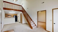 This two-story home in North Canton, Ohio offers a well-organized layout spread across two levels. The main floor serves as the heart of the home, encompassing a welcoming entrance, a spacious living room with soaring vaulted ceilings, and a combined kitchen and dining area. The kitchen is equipped with light wood cabinetry, a double stainless steel sink, gas range, dishwasher, and a black refrigerator, all set on tile flooring. The living room features plush carpeting and is anchored by a striking wood-banistered staircase that rises to the upper level. A patio, laundry, utility room, and closet round out the main floor. Upstairs, the loft-style upper level is highlighted by dramatic vaulted ceilings with a skylight that fills the space with natural light, a ceiling fan, and an open railing overlooking the floor below. The primary bedroom features vaulted ceilings, a ceiling fan, a window with natural light, and two closets. A second bedroom and a full bathroom with a tub/shower combination and tile flooring complete the upper level. Carpeting throughout the bedrooms and living areas adds warmth, while the open, airy design of the home creates a comfortable and functional living environment.