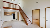This two-story home in North Canton, Ohio offers a well-organized layout spread across two levels. The main floor serves as the heart of the home, encompassing a welcoming entrance, a spacious living room with soaring vaulted ceilings, and a combined kitchen and dining area. The kitchen is equipped with light wood cabinetry, a double stainless steel sink, gas range, dishwasher, and a black refrigerator, all set on tile flooring. The living room features plush carpeting and is anchored by a striking wood-banistered staircase that rises to the upper level. A patio, laundry, utility room, and closet round out the main floor. Upstairs, the loft-style upper level is highlighted by dramatic vaulted ceilings with a skylight that fills the space with natural light, a ceiling fan, and an open railing overlooking the floor below. The primary bedroom features vaulted ceilings, a ceiling fan, a window with natural light, and two closets. A second bedroom and a full bathroom with a tub/shower combination and tile flooring complete the upper level. Carpeting throughout the bedrooms and living areas adds warmth, while the open, airy design of the home creates a comfortable and functional living environment.