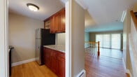 This thoughtfully designed three-floor home offers a cohesive blend of classic finishes and practical functionality throughout. The kitchen is a standout feature, equipped with rich cherry wood cabinetry, granite countertops, stainless steel appliances including a refrigerator, electric range, and microwave, and a tile backsplash — all set over warm hardwood flooring. An adjacent half bathroom on the main level features a pedestal sink with chrome fixtures and a framed mirror, providing added convenience for guests. Open living areas are finished with crown molding, hardwood floors, and neutral warm-toned walls, creating a bright and welcoming ambiance. Sliding glass doors in the main living space invite natural light and provide access to the outdoors. A staircase with a classic white balustrade connects all three floors seamlessly. The upper level includes carpeted bedrooms with windows that frame views of surrounding greenery, a full bathroom with granite vanity, cherry cabinetry, and a tub-shower combination, and tile flooring. The lower level offers a generously sized carpeted recreation room with baseboard heating, additional storage, and a dedicated laundry area equipped with a full-size washer and dryer. Throughout, baseboard heating ensures year-round comfort in every room.