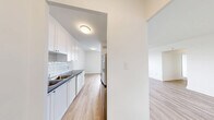 Located at 7 Elizabeth St N in Mississauga, Ontario, this well-appointed unit offers three bedrooms and one bathroom across a generously sized single floor. The interior is finished with light-toned laminate wood flooring throughout, creating a bright and cohesive aesthetic that flows from room to room.

The kitchen is designed with clean white cabinetry, subway tile backsplash, a double-basin sink, and dark countertops, offering a functional galley-style layout. It opens toward the living areas, enhancing the sense of connectivity throughout the unit.

Multiple living areas provide flexible space for dining, lounging, or other uses. These rooms are bathed in natural light, with large windows framing elevated city views of the Mississauga skyline — a standout feature of the unit. Baseboard heating units are positioned beneath the windows in several rooms.

The three bedrooms are well-sized, with the primary bedroom offering a comfortable footprint. All bedrooms share the same warm wood-look flooring and crisp white walls, contributing to a clean, neutral palette throughout.

The bathroom features a white vanity with an integrated sink, light countertop surface, and a large mirror, maintaining the unit's consistent modern and minimal aesthetic. A dedicated closet and hallway complete the practical layout of this bright, move-in ready home.