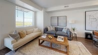 This thoughtfully designed three-story space offers a clean, contemporary aesthetic carried consistently across each level. The kitchen serves as a central highlight, featuring dark espresso cabinetry, granite countertops, and a spacious island with an integrated sink and bar seating for three. Black appliances, including a french door refrigerator and range, complement the cabinetry, while warm wood-look flooring grounds the space. The kitchen flows naturally into a dining area and an open living room, where large windows invite generous natural light and views of the surrounding landscape. The living area accommodates multiple seating arrangements, with herringbone-patterned wood flooring adding visual texture.

Bedrooms are carpeted and quietly appointed, each with window blinds and soft neutral tones. A nursery-configured room includes carpet and a window overlooking the exterior. Bathrooms feature wood-look flooring, granite vanity tops, and dark cabinetry consistent with the kitchen's design language. A compact powder room provides convenience, while a full bath includes a tub-shower combination. A dedicated laundry closet houses a full-sized washer and dryer. The staircase connects all three levels, providing an efficient and cohesive vertical layout throughout.