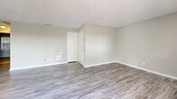 Located at 1191 Carlton Arms Circle in Bradenton, Florida, this single-floor, two-bedroom, one-bathroom home offers a practical and comfortable layout. The open living room features light gray wood-look vinyl flooring, neutral-toned walls, and a sliding glass door that fills the space with natural light and provides access to an outdoor area. A secondary window adds to the brightness, creating an airy, welcoming atmosphere. A closet with louvered bifold doors provides convenient storage within the living area.

The kitchen is well-appointed with white cabinetry, a full suite of white appliances including an electric range, dishwasher, and refrigerator, and a double basin sink. A skylight-style overhead fixture provides ample task lighting, while the wood-look flooring ties the space together seamlessly.

Both bedrooms are carpeted in warm neutral tones and feature windows that bring in natural light and outdoor views of surrounding greenery. Each bedroom is equipped with a closet. The bathroom is cleanly finished with a white vanity, wood-look flooring, and a full tub-shower combination with tiled surround. Throughout the home, consistent neutral paint tones and clean finishes create a cohesive, move-in ready environment.