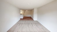 Located at 801 S Lyon St in Santa Ana, CA, this single-floor unit offers a straightforward, functional layout designed for comfortable everyday living. The entryway opens into a spacious living area that combines wood-style flooring near the entrance with plush carpeting throughout the main living space, creating a warm and inviting atmosphere. A textured ceiling and a wall-mounted HVAC unit are present, along with vertical blinds covering a sliding door that brings in natural light. The open layout provides a clear sightline into the kitchen area, which is anchored by a ceiling fan overhead. The kitchen features white cabinetry extending to the upper walls for ample storage, a speckled countertop with a double stainless steel sink, and a gas range with an overhead ventilation hood. The flooring transitions to wood-style planks in the kitchen and hallway areas. The bathroom is well-appointed with a wide vanity topped with a speckled countertop, a large mirror, built-in wall shelving, and a separate water closet with a tub-shower combination. Wood-style flooring continues throughout the bathroom and hallway, tying the space together with a cohesive look. Overall, the unit presents a clean, neutral palette that provides a versatile canvas for personalization.