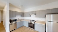 Located at 80 South Rd, Unit 109 in Farmington, CT, this well-designed two-bedroom, one-bathroom residence offers a thoughtful layout across a single floor. The contemporary kitchen is a standout feature, equipped with sleek flat-front gray cabinetry extending to the ceiling, light quartz countertops, and a full suite of stainless steel appliances including a range, dishwasher, microwave, and refrigerator. Light wood-look flooring runs throughout the main living and kitchen areas, lending warmth and continuity to the space. The open living area benefits from large windows that invite an abundance of natural light, complemented by a wall-mounted mini-split system for year-round comfort. Both bedrooms are finished with plush wall-to-wall carpeting, and each features a window with outdoor views and its own mini-split unit. The primary bedroom offers a generous footprint with ample space for furnishings. The full bathroom is appointed with a gray vanity, a large mirror, marble-style tile flooring, and a shower-tub combination. A dedicated closet and hallway complete the layout, providing practical storage and easy flow between rooms. Clean white walls and recessed lighting throughout give the unit a bright, modern aesthetic.